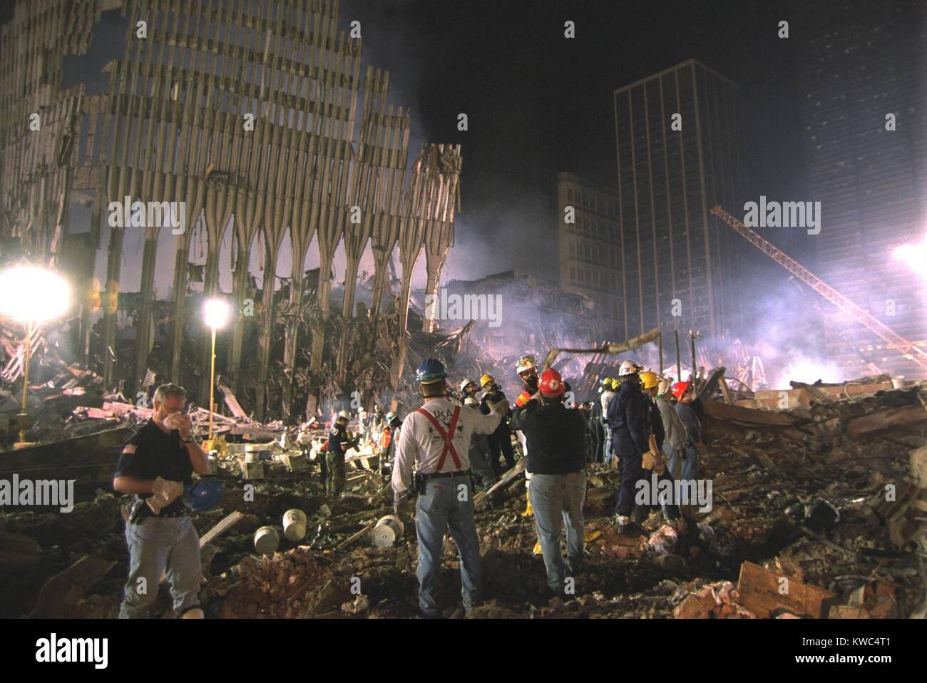 On the south west area of Ground Zero a bucket line removes debris at night, Sept 17, 2001. At left a section of WTC 1, the North Tower still stands. World Trade Center, New York City, after September 11, 2001 terrorist attacks. (BSLOC 2015 2 92) Stock Photo
