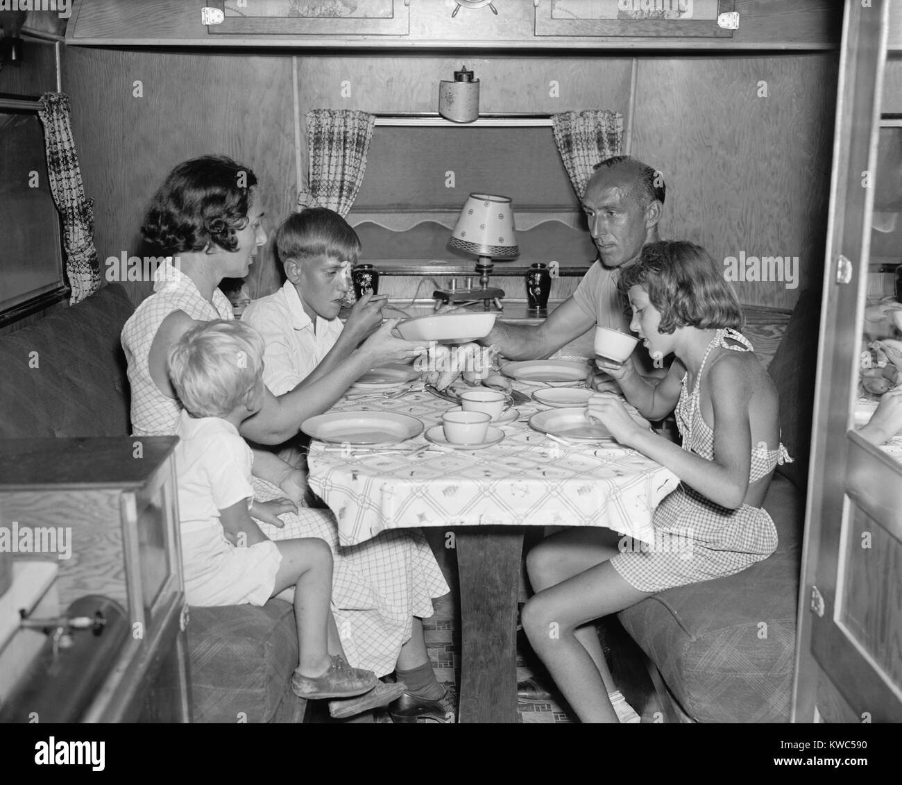 American family dining at the table in their Trailer Camper. June 4, 1937. In the 1930s, in spite of the Great Depression, Travel Trailers costing as much as $4700, were popular for recreational tourism. (BSLOC 2015 14 144) Stock Photo