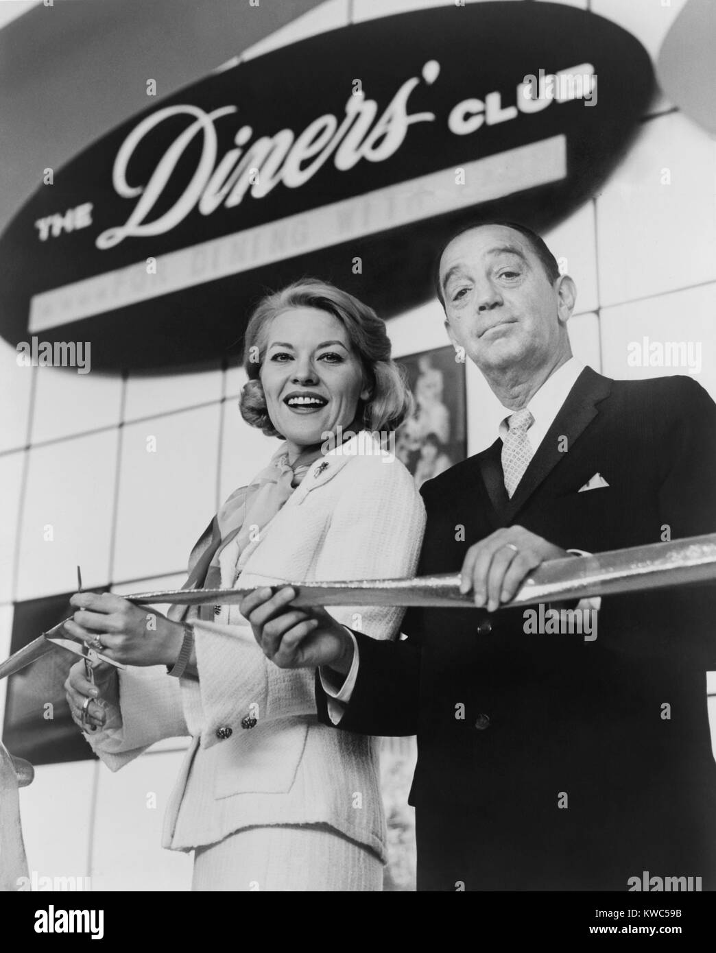 Ralph Schneider assists Patti Page cutting ribbon to open Diners' Club exhibit at 1964 World's Fair. Diners Club was the first independent credit card company in 1950. Schneider co-founded the company with Frank McNamara, who sold out his interest in 1952. (BSLOC 2015 14 152) Stock Photo