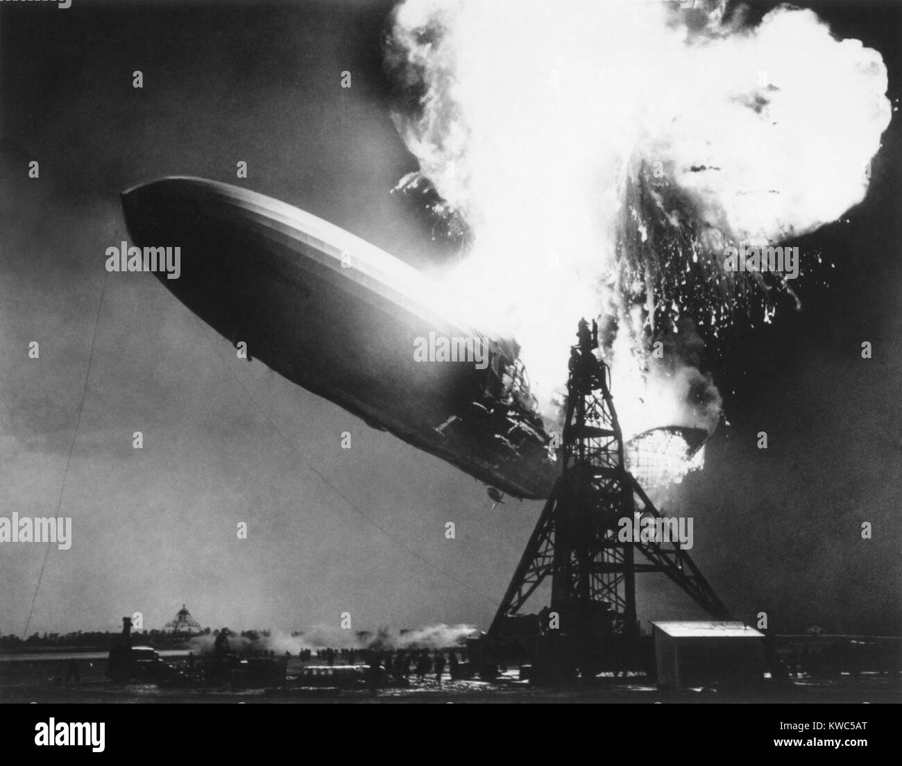 The German passenger airship Hindenburg seconds after catching fire, May 6, 1937. At 200 feet above the ground, flames erupt on top and in the back of the ship. It descended as it burned, reaching the ground as a metal skeleton after the fabric covering burned away in less than 30 seconds. (BSLOC 2015 14 188) Stock Photo