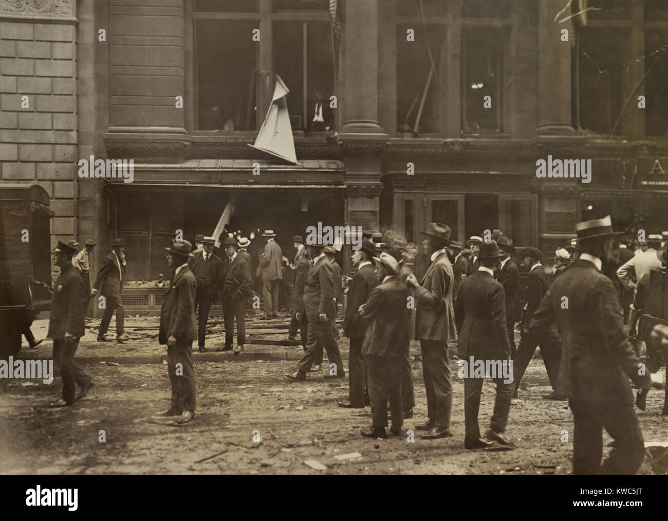 Bomb blasted Wall Street offices of the Buffalo, Rochester and Pittsburgh Railway. Employees can be seen through the blown out windows as a curious crowd mills on the street below. Sept. 16, 1920. (BSLOC 2015 15 177) Stock Photo