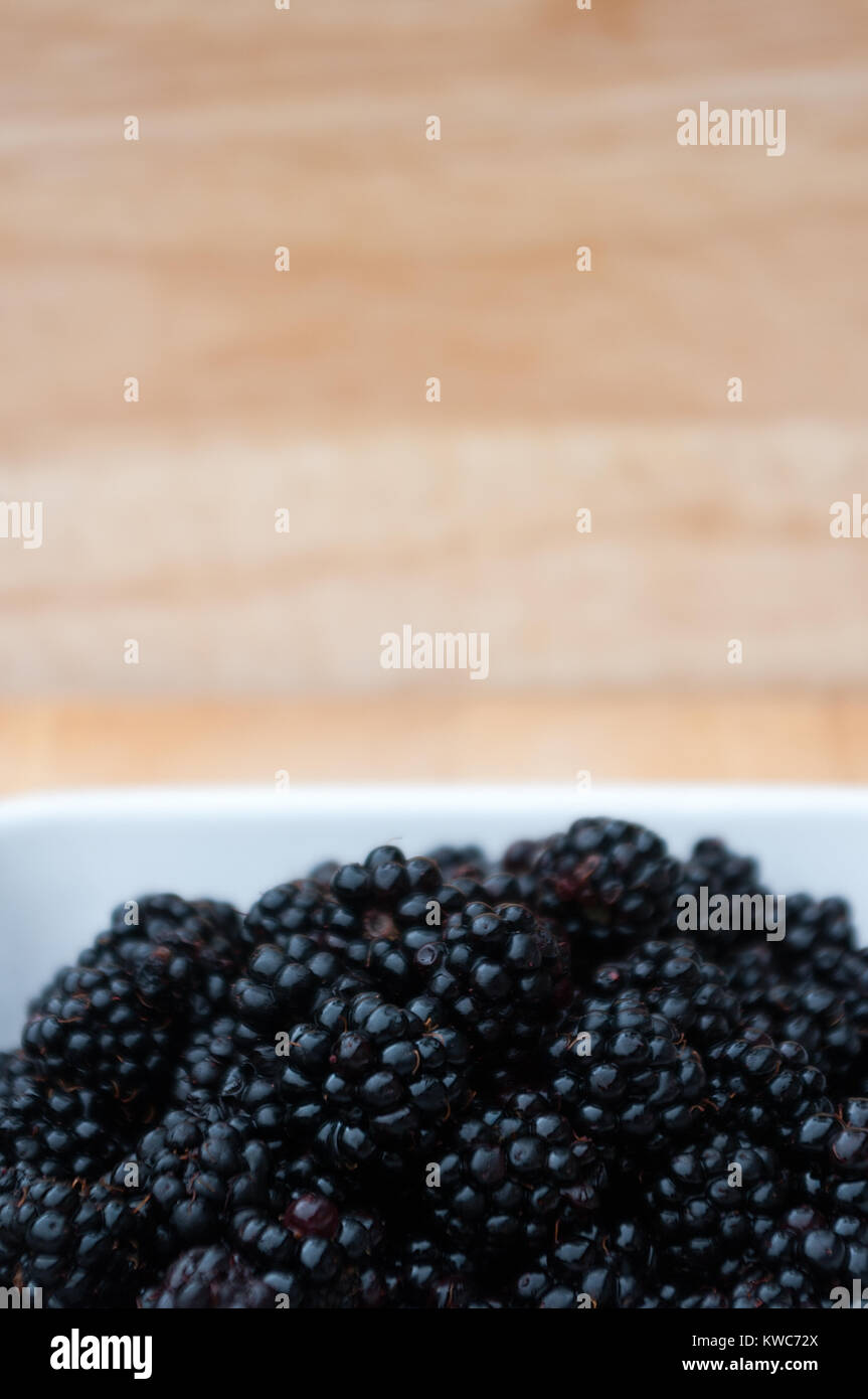 Blackberries in a white bowl with blurred background. Space for copy. Stock Photo