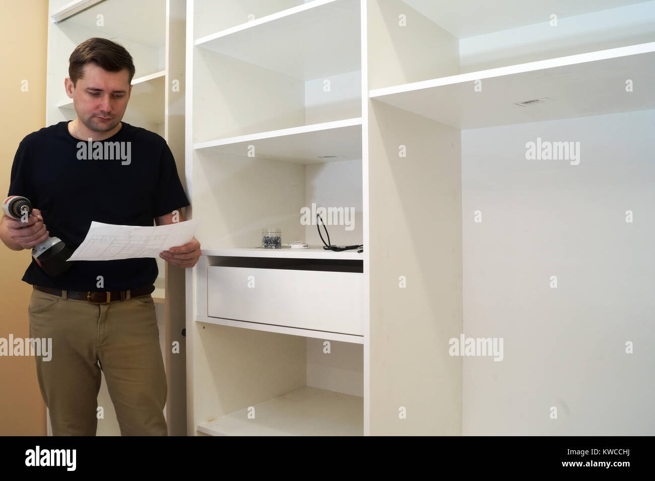 Master reading instruction of installation wardrobe. Assembly cabinets in a bed. Stock Photo