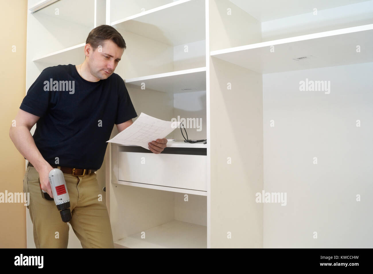 Cabinet assembly. Man with a screwdriver installing bi wardrobe. Stock Photo