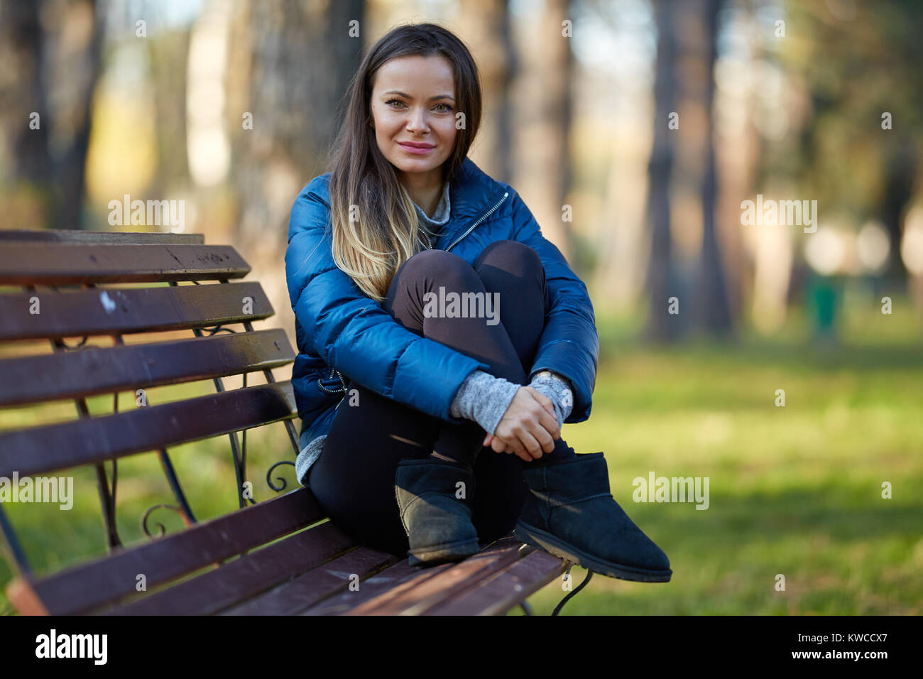 Young woman sitting on a bench in the park Stock Photo - Alamy