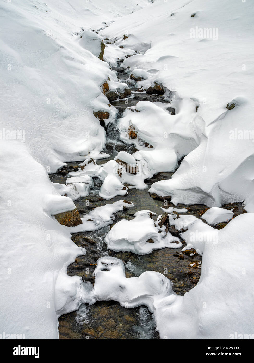 Mountain river flowing through snow valley Stock Photo - Alamy