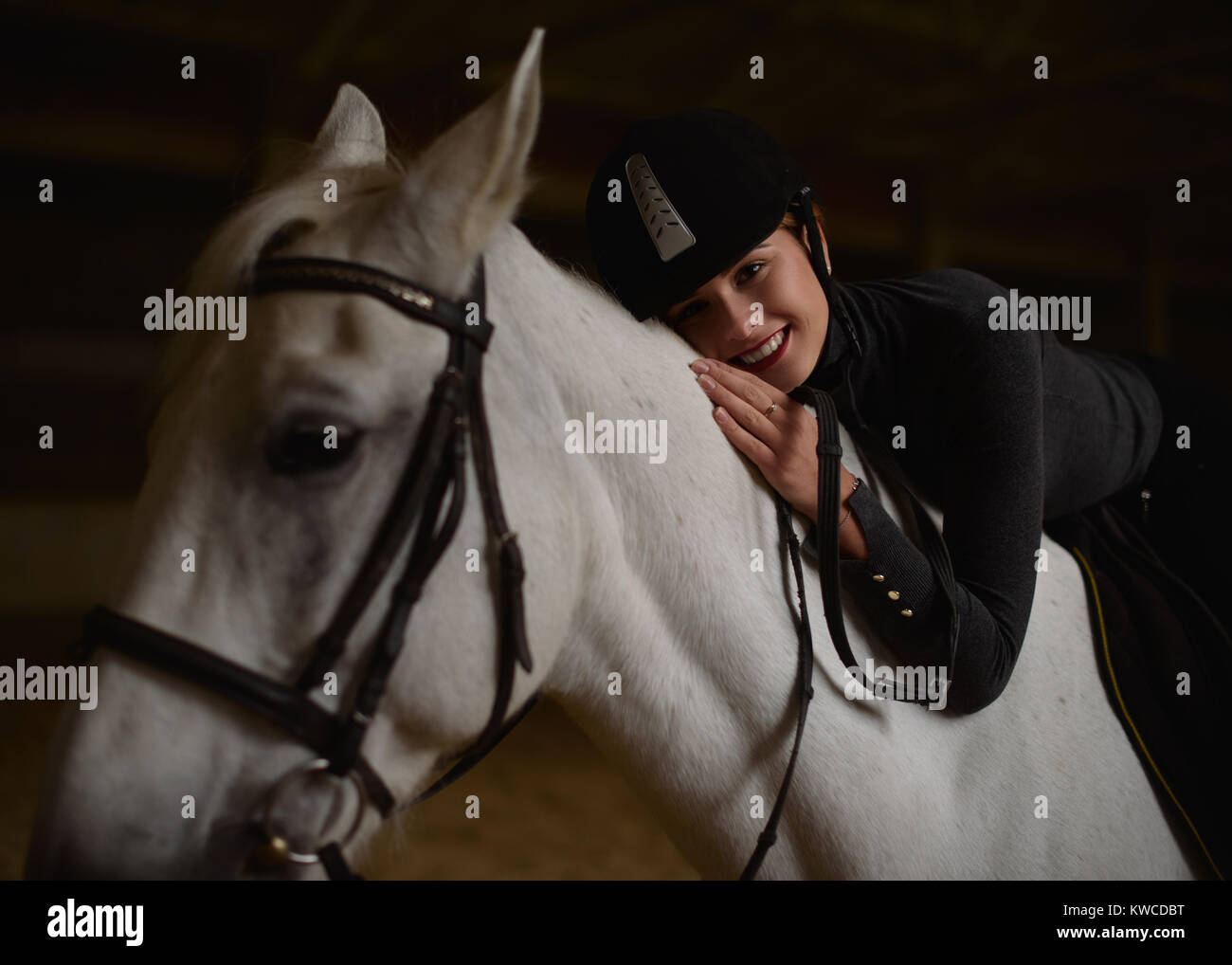 Woman sits on white horse and hugs its neck Stock Photo Alamy