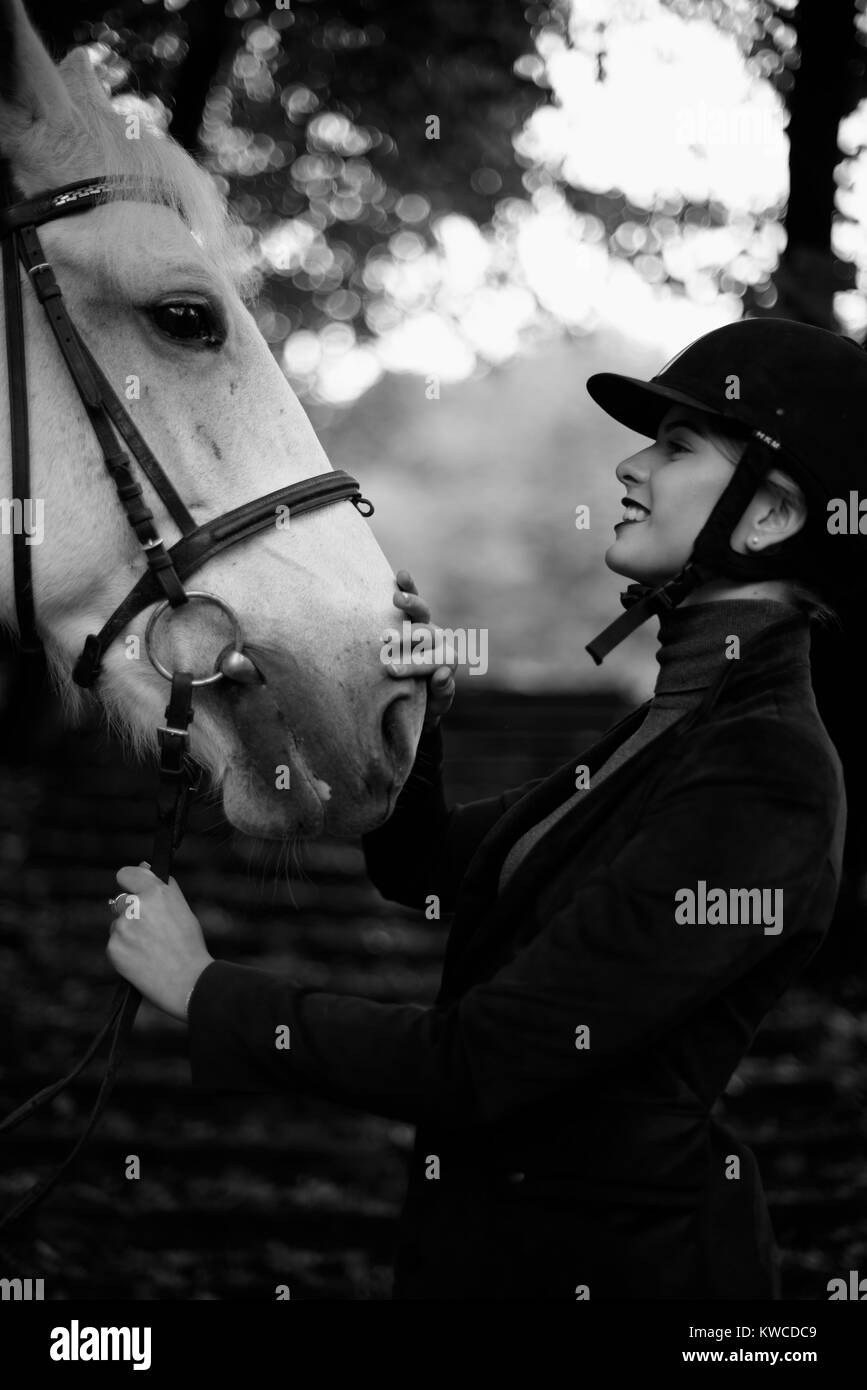 Blck and white photo of pretty lady stroking horse's head. Stock Photo