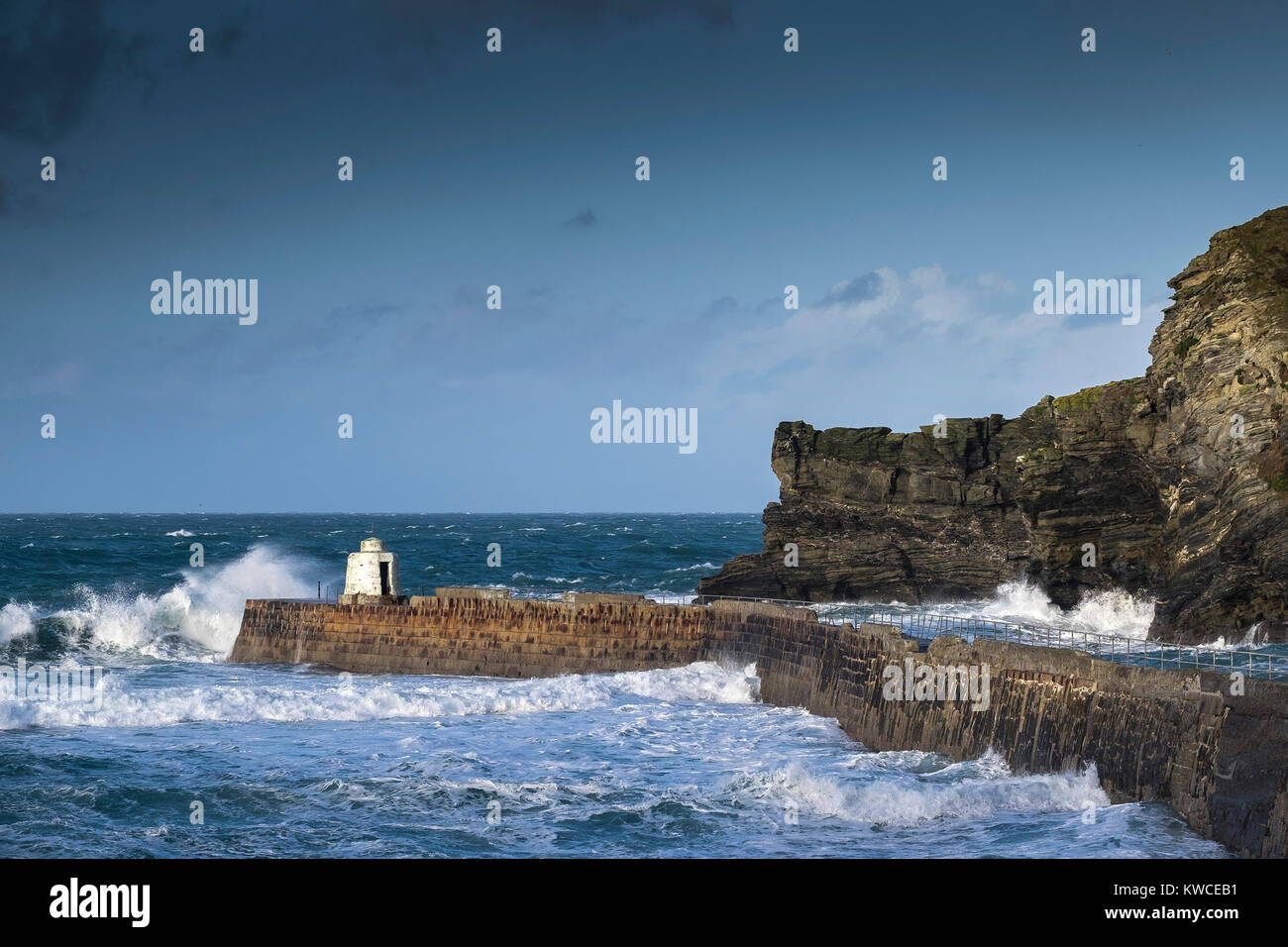 UK weather - Rough seas breaking over the pier at Portreath Harbour in Cornwall. Stock Photo