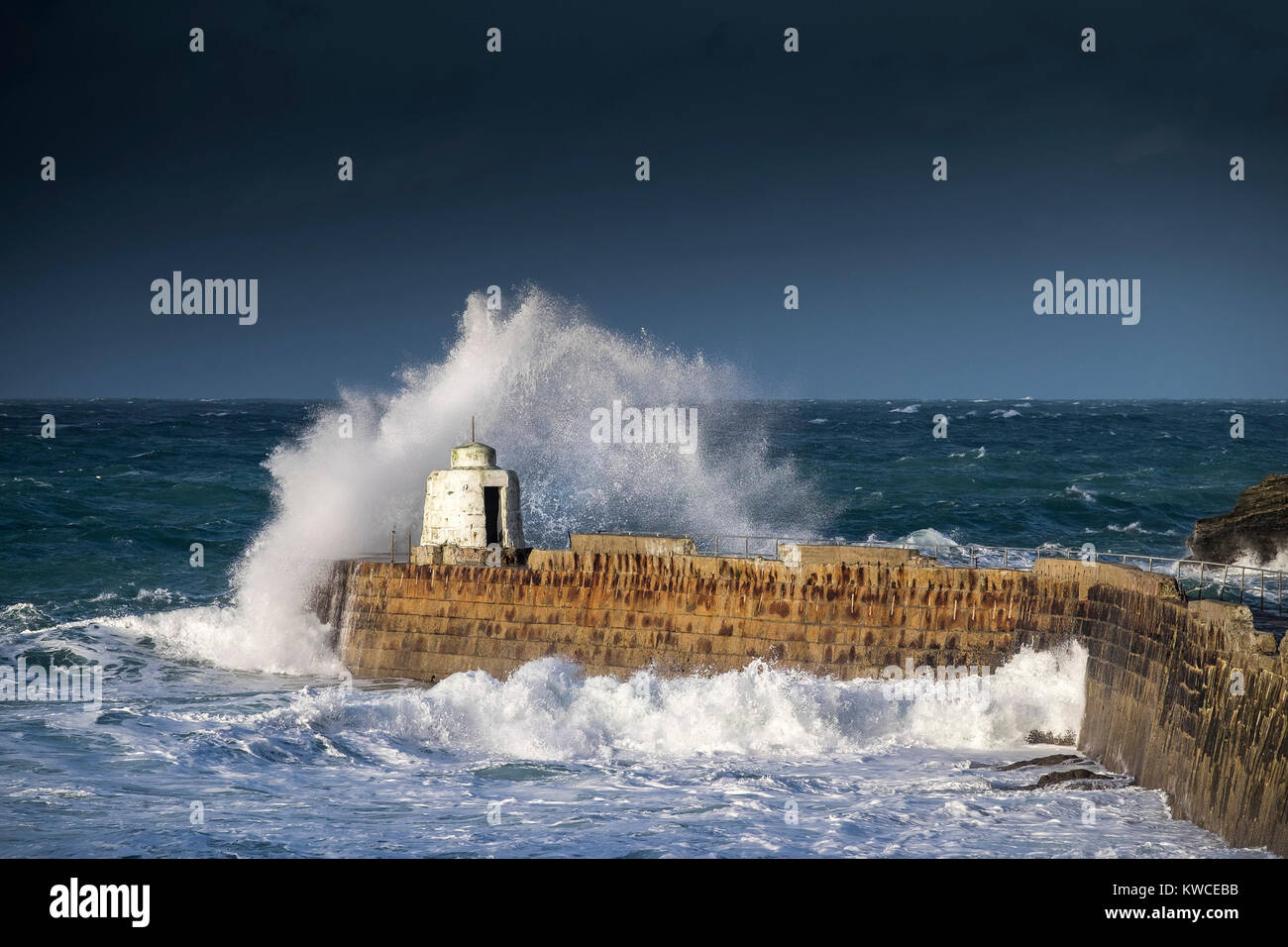 UK weather - Gale force winds driving huge waves over the pier at Portreath Harbour in Cornwall. Stock Photo