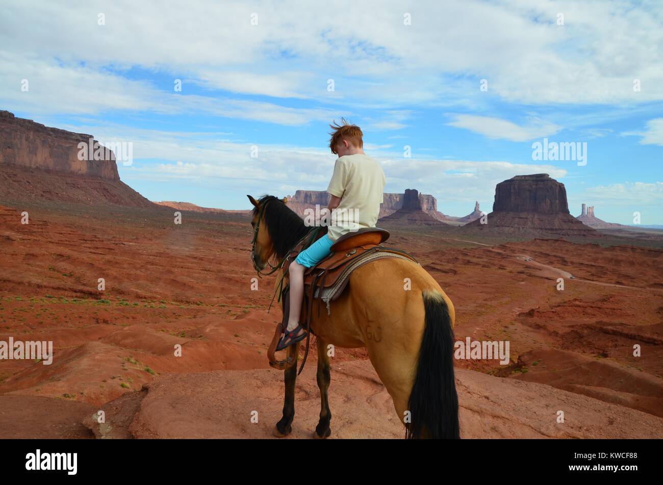 red haired boy on horse in monument valley in shorts Stock Photo