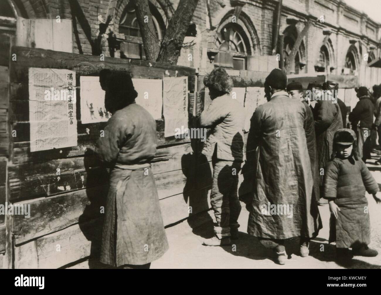 Chinese residents of Manchuria read Japanese announcements. They report establishment of the Republic of Manchukuo with Mr. Henry Pu-Yi, as its chief executive. Japan essentially annexed Manchuria and installed the former child Emperor as its puppet ruler. 1934. - (BSLOC 2014 15 157) Stock Photo