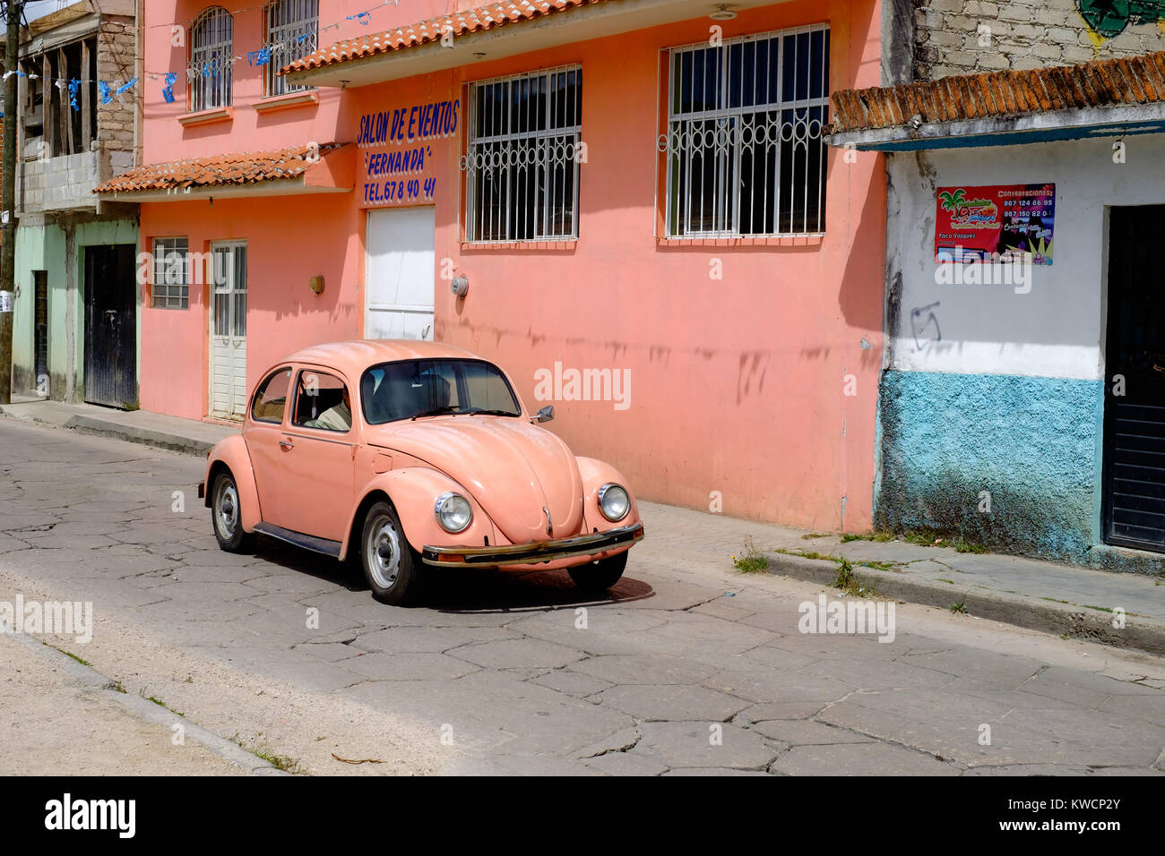 A pink Volgswagen Beetle adjacent to a pink wall in San Cristóbal de Las Casas, Mexico Stock Photo