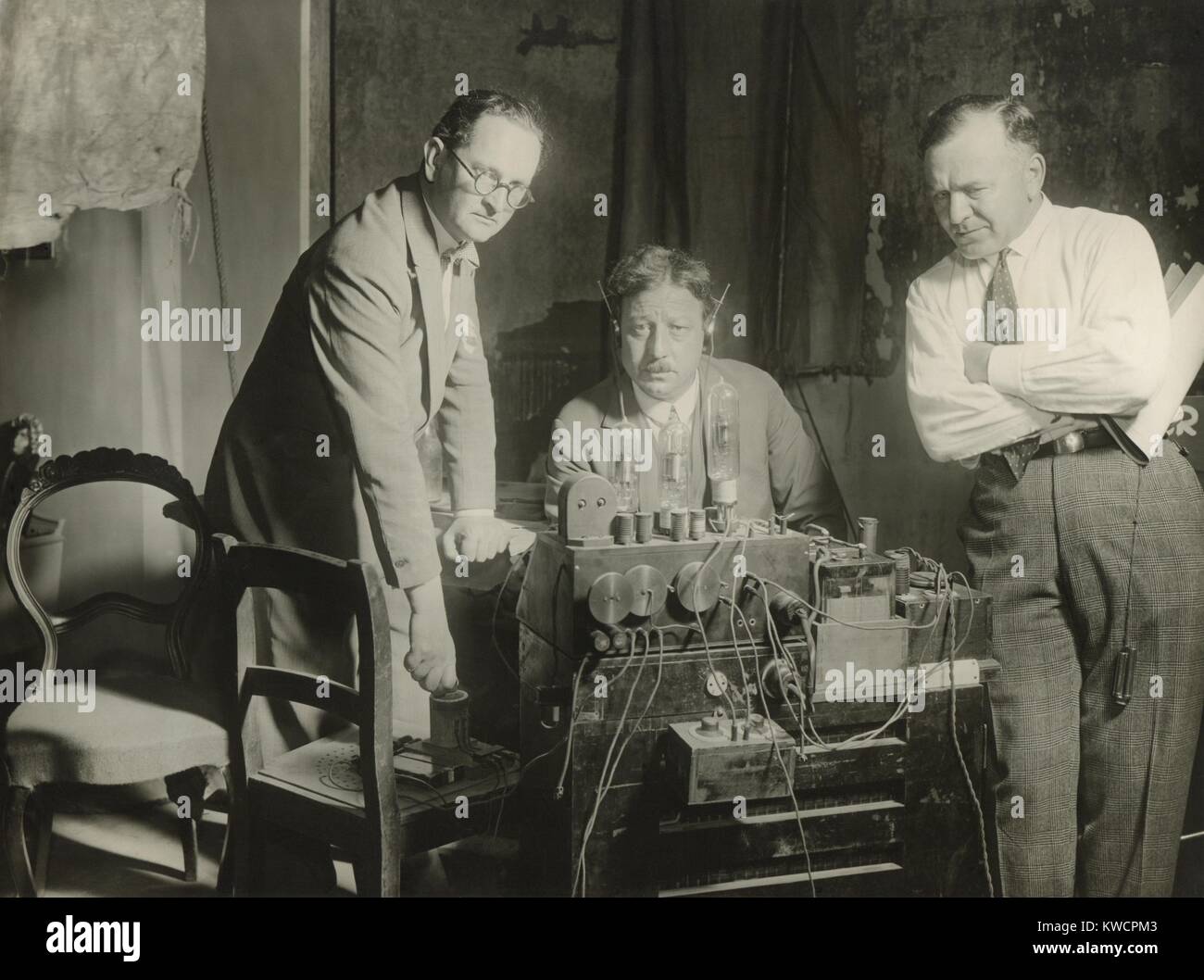 Inventor, Joseph Massolle (center), listening to the first screening of German Movietone News. He is using a machine called a Trigeron (Work of Three), invented in 1919 by himself and Josef Engl (left) and Hans Vogt (right). Their technology for a sound track on movie film became the industry standard in the 1920s. - (BSLOC 2014 17 121) Stock Photo