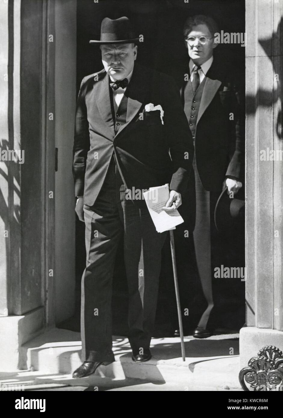 Prime Minister Winston Churchill leaving 10 Downing Street to speak to Parliament on June 18, 1940. He announced Britain has more than 1,250,000 men under arms and Britain would fight alone 'for years' if necessary. Behind him is Brendan Bracken, a Conservative Party Parliamentary Private Secretary to the Prime Minister. The Germans had just defeated France and British troops had retreated from Dunkirk to England. - (BSLOC 2014 17 34) Stock Photo