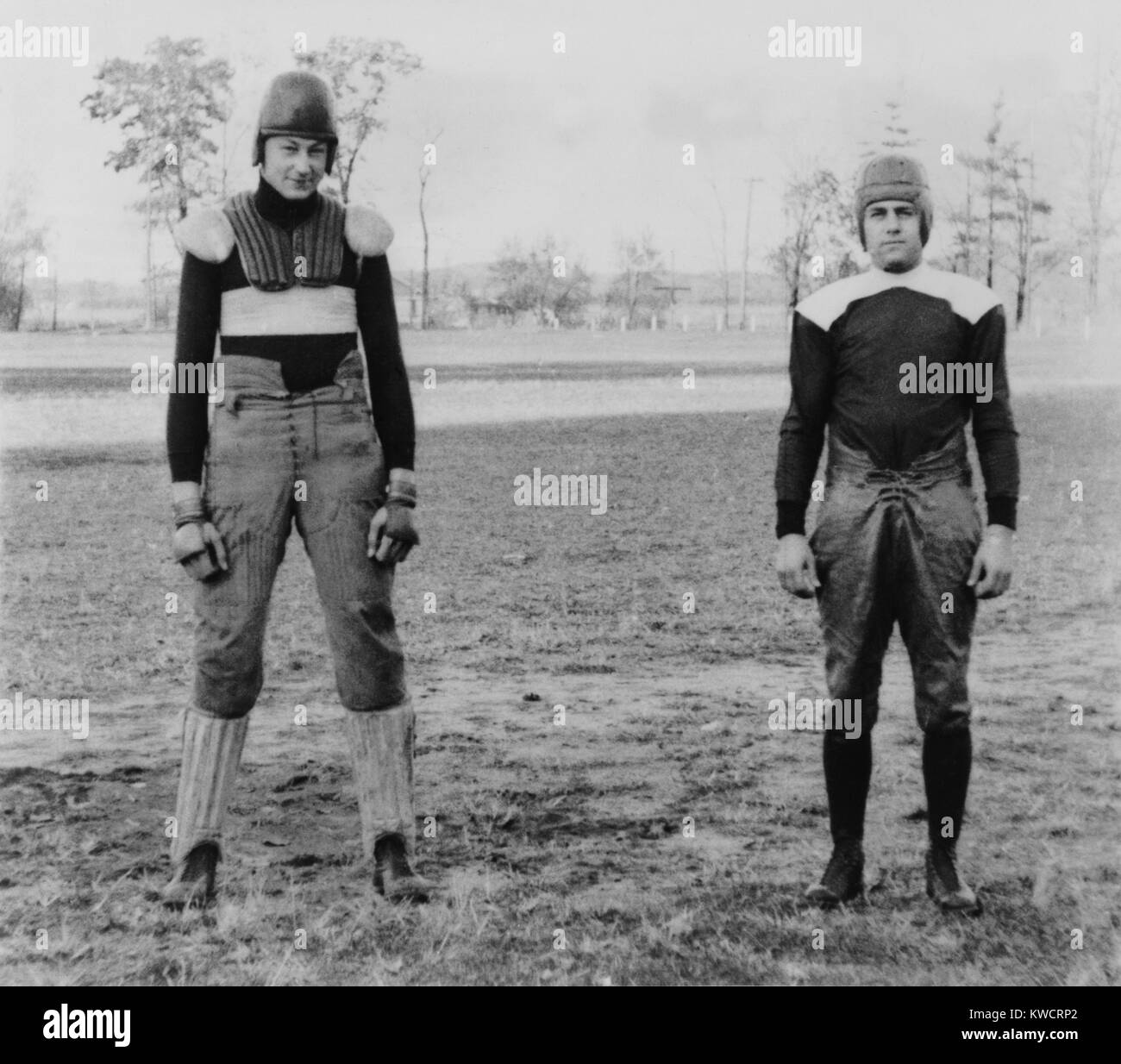 Notre Dame University football players wearing old and new football uniforms. At left is a football suit of the 1880's with external padding. At right is a 'modern' uniform with shoulder pads worn under the jersey. South Bend, Indiana. Ca. 1930. - (BSLOC 2015 1 220) Stock Photo