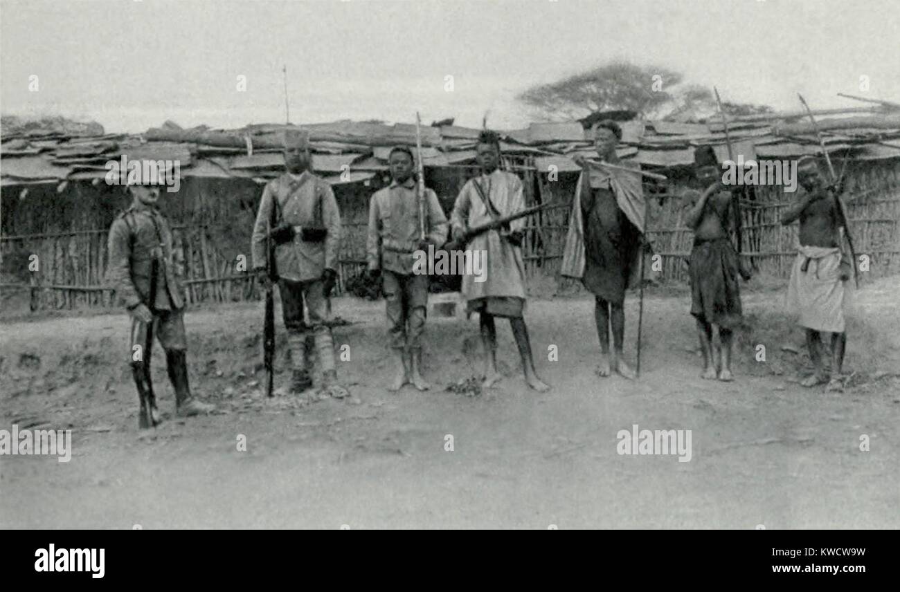 World War 1 in Africa. The transformation the German Askaris (native soldiers). At right are three natives with their traditional weapons. To their right are two Askari in training and then a uniformed and fully equipped Askari. At far left is their German officer. Ca. 1915-17. (BSLOC 2013 1 37) Stock Photo