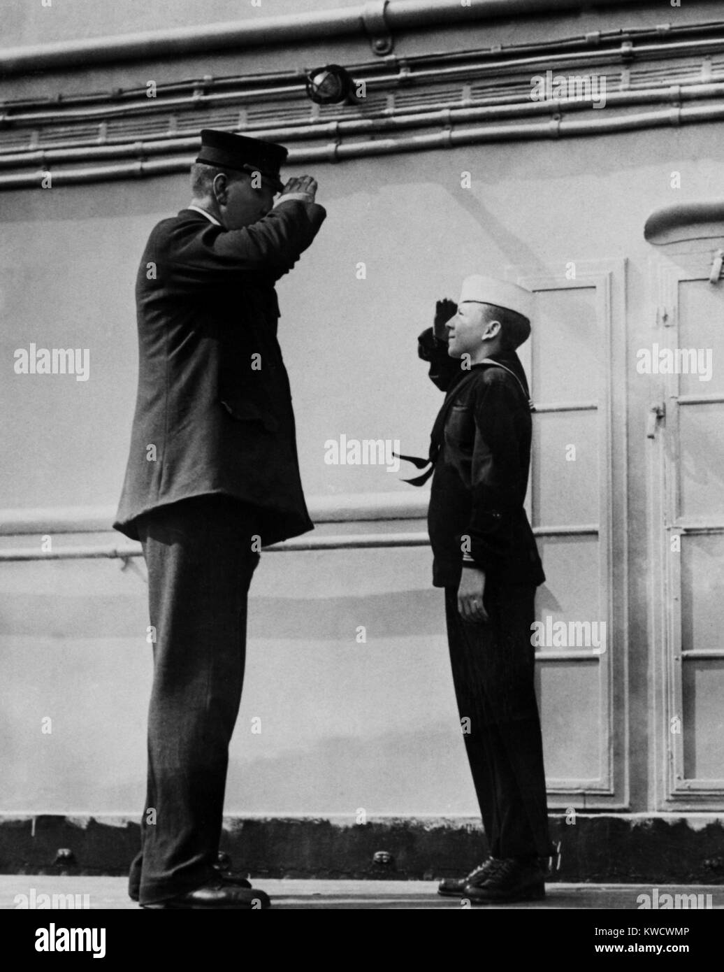 On the WW1 troop ship, USS Leviathan, the ships tallest and shortest sailor salute each other. The taller is the Chief Machinists Mate (BSLOC 2017 1 17) Stock Photo