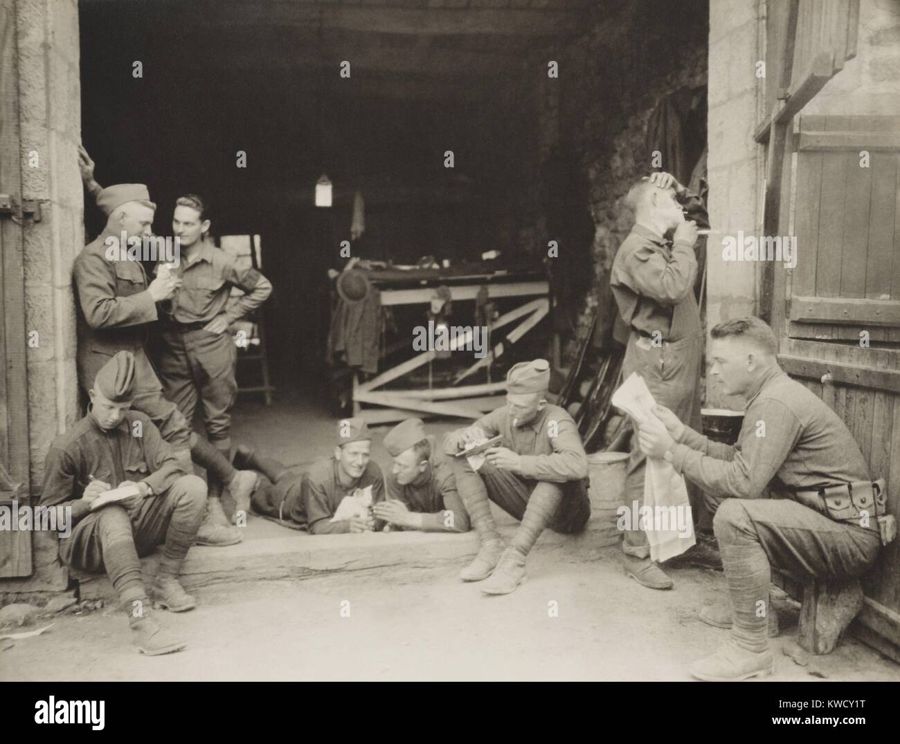 US Army Military Police off duty in France, Aug, 31, 1918. The men are talking, writing letters, cuddling a kitten, polishing a gun, shaving, and reading a magazine (BSLOC 2017 1 18) Stock Photo