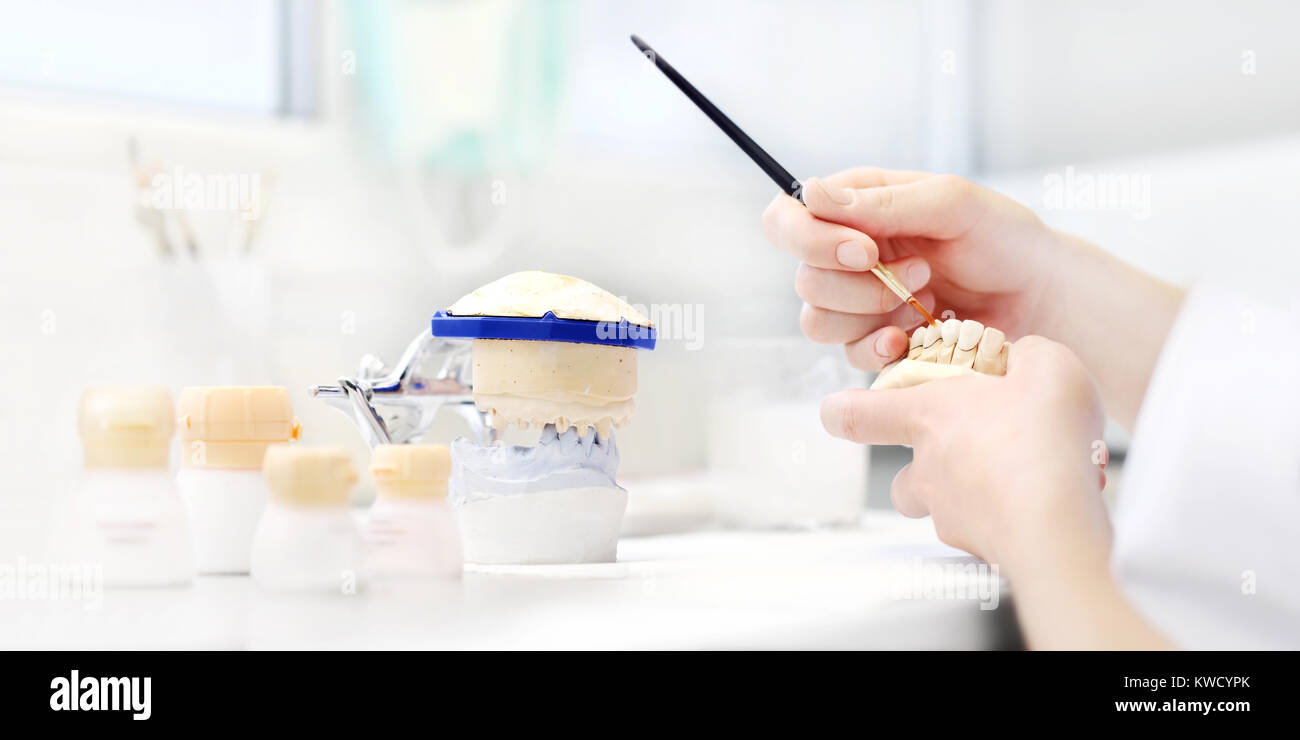 Dental technician hands working with tooth dentures in his laboratory