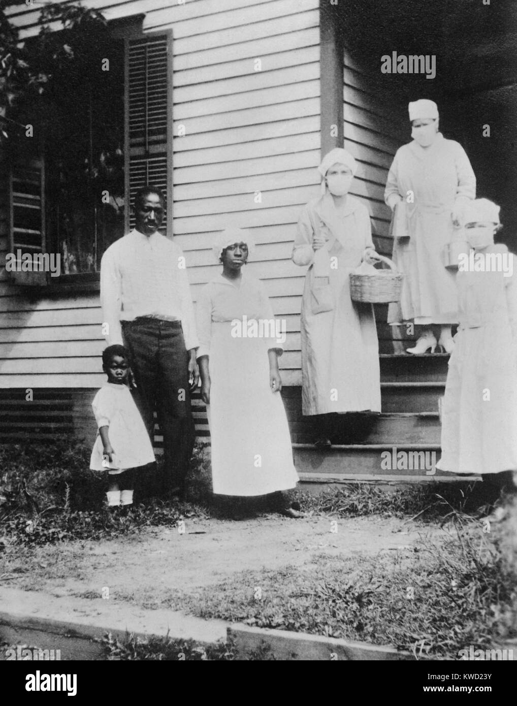 African American family receiving food from the American Red Cross during the Flu epidemic, Oct. 1918. His wife and mother of the family had just died, and masked canteen workers assisted the family  (BSLOC 2017 20 128) Stock Photo