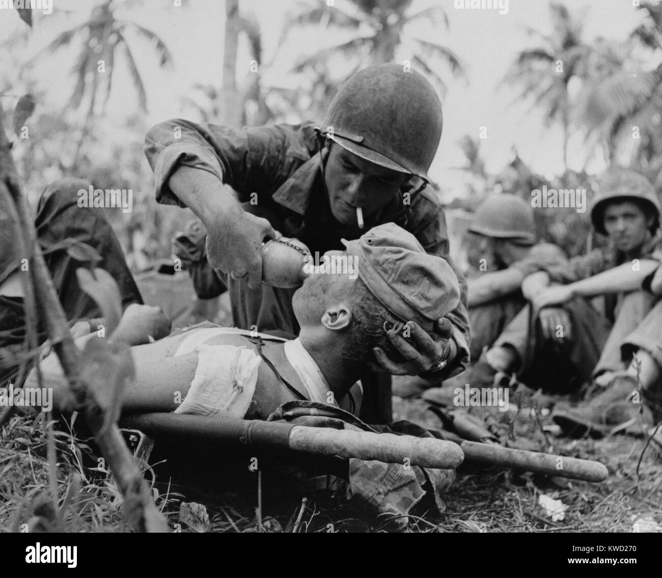 US Navy corpsman gives a drink to wounded Marine on Guam, July 1944, during World War 2.  (BSLOC 2017 20 187) Stock Photo