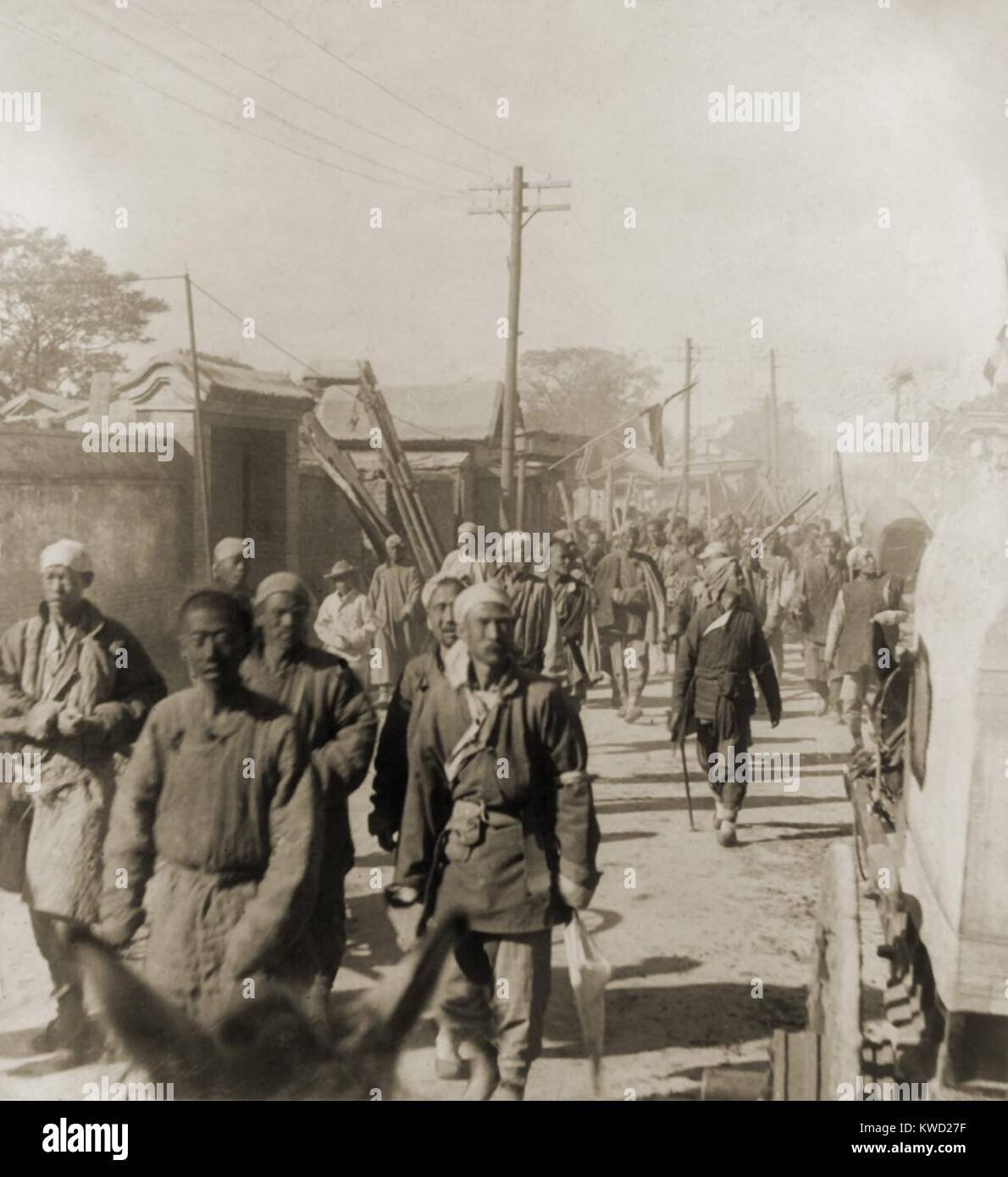 Company of Boxers walking on a street in Tianjin (Tientsin), China, in June 1900. They started the Boxer Rebellion against Chinese Christians, European missionaries, and foreign nationals in northwest China. Many came from the country, originally armed only with sticks, their ritual gymnastics, and superstitions. The 1963 movie, 55 DAYS AT PEKING, was based on the war  (BSLOC 2017 20 24) Stock Photo