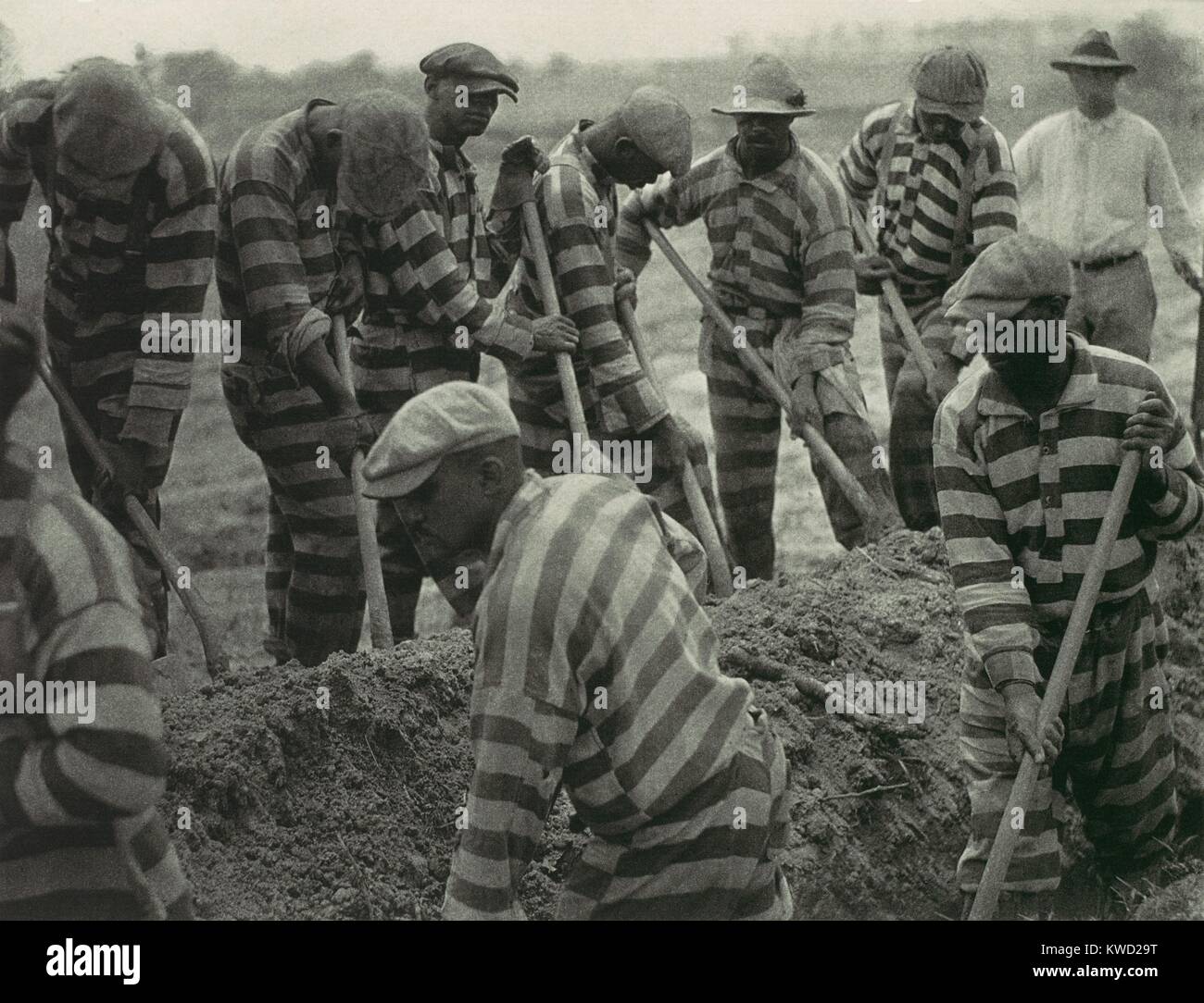 Prison Work Crew in the American South, 1929-30, by Doris Ulmann. The chain gang of 9 workers is digging, as one guard with a rifle looks on  (BSLOC 2017 20 73) Stock Photo