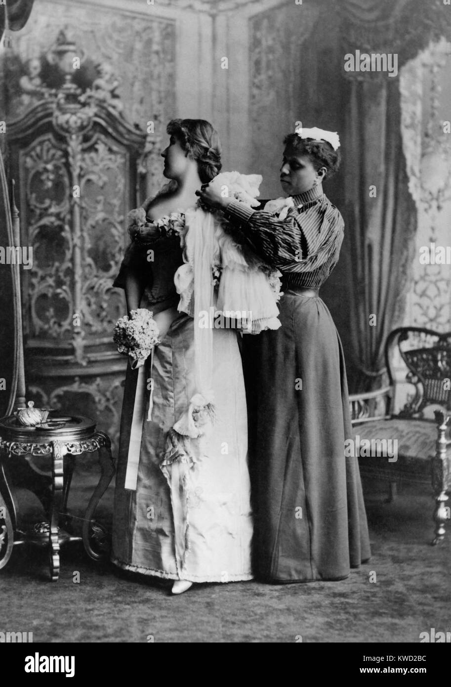 African American ladys maid helps a wealthy woman get dressed in luxurious evening gown, 1897.  (BSLOC 2017 20 111) Stock Photo