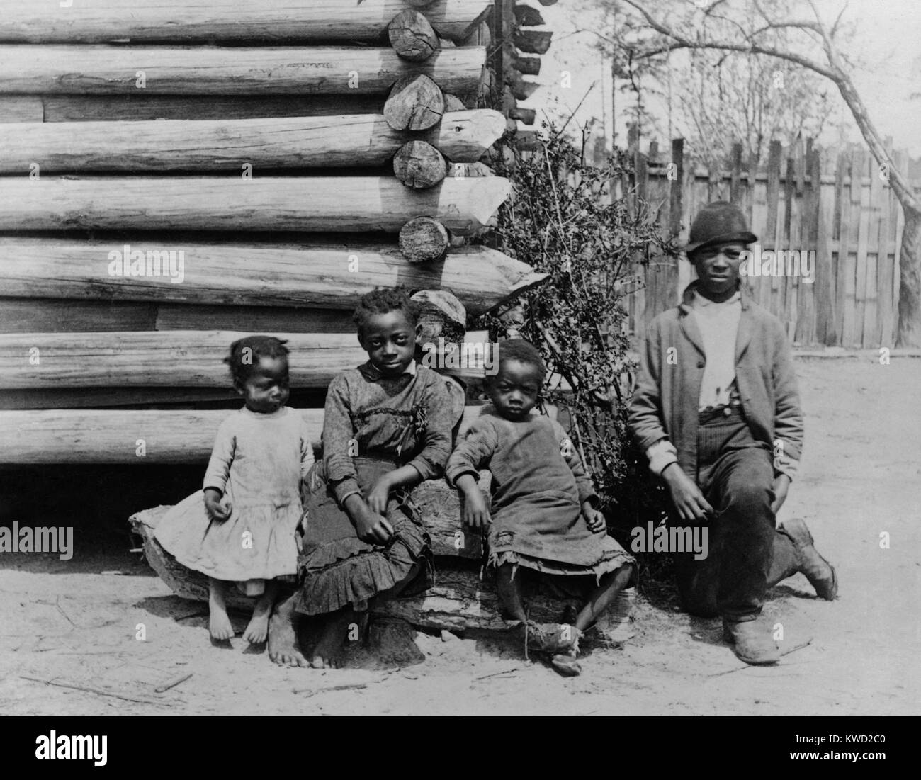 African American teenager and three children posed by log building