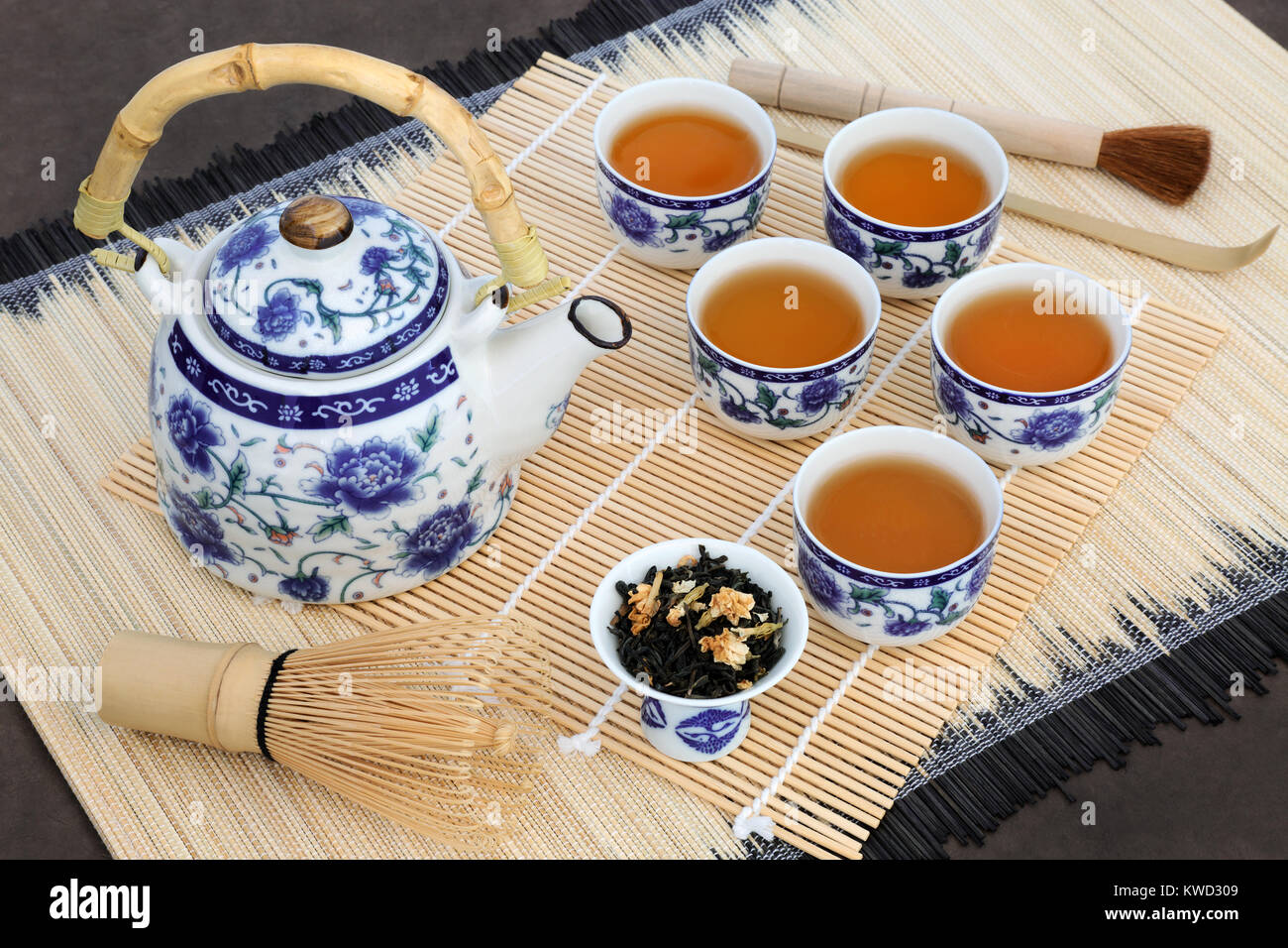 Japanese jasmine tea ceremony with teapot, cups, leaves,  whisk, brush and scoop on bamboo. Also used in herbal medicine. Stock Photo