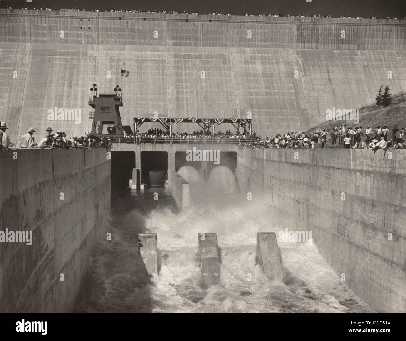 Official opening of the partially completed Friant-Kern Canal, July 9, 1949. When completed the canal would irrigate 600,000 acres of arid land in the central valley of southern California. Spectators lined on both sides and are along top of wall in the background. July 9, 1949. (BSLOC_2014_13_228) Stock Photo