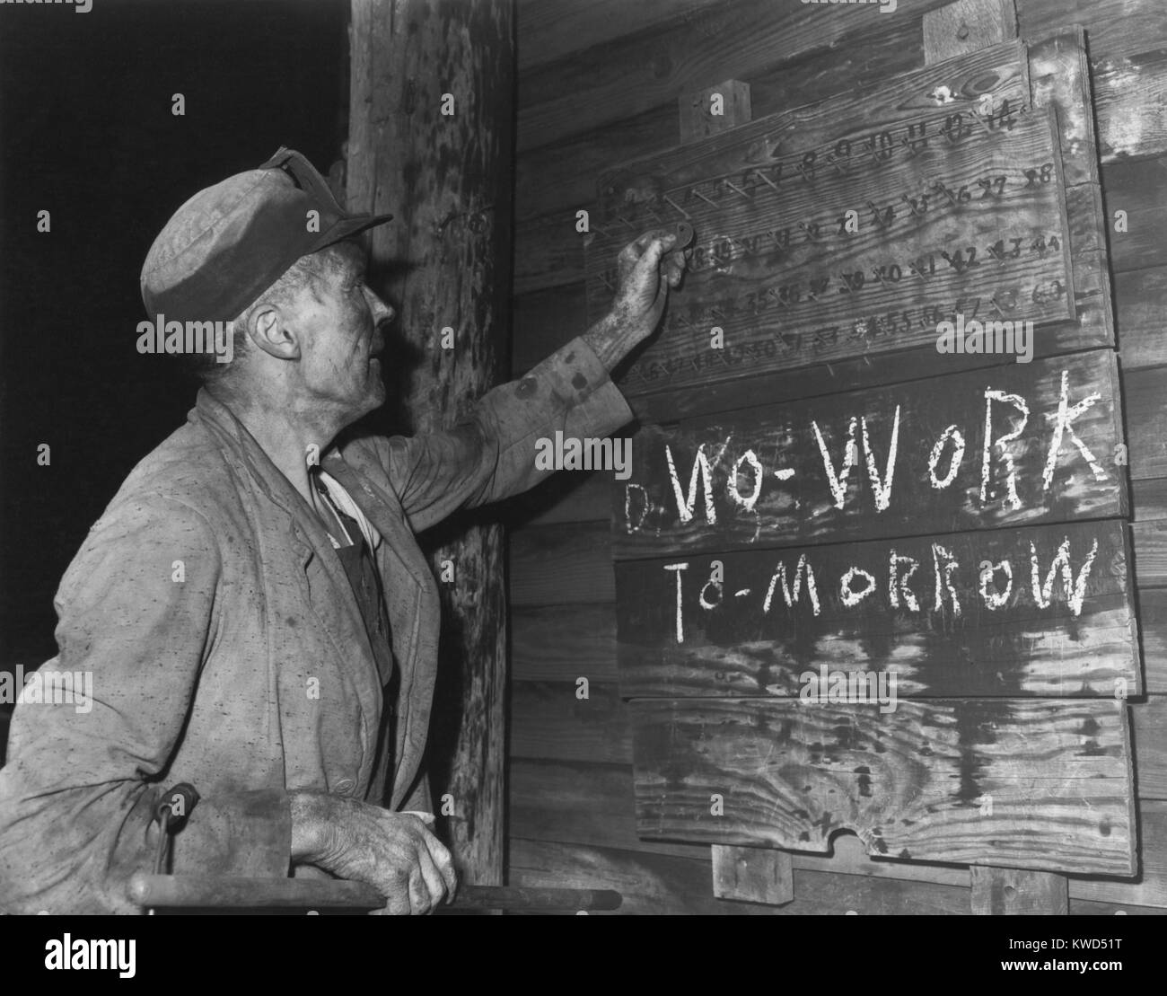 A coal loader putting up his check at the end of day's work on Friday, Sept. 13, 1946. Below the board is a notice in chalk writing, 'No Work Tomorrow' with 'N' written backwards. Harlan County, Kentucky. Photo by Russell Lee. (BSLOC 2014 13 234) Stock Photo