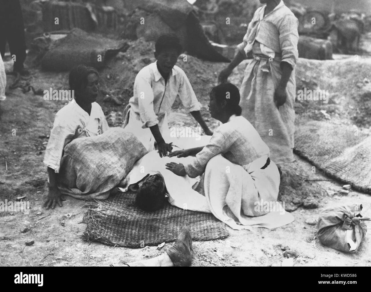 A Korean family mourns their murdered father, killed in mass executions at Chonju by North Koreans. Victims were mostly South Korean police and youth group leaders who were forced to dig a pit, then killed and thrown in it. Sept 17, 1950. Korean War, 1950-53. (BSLOC 2014 11 238) Stock Photo