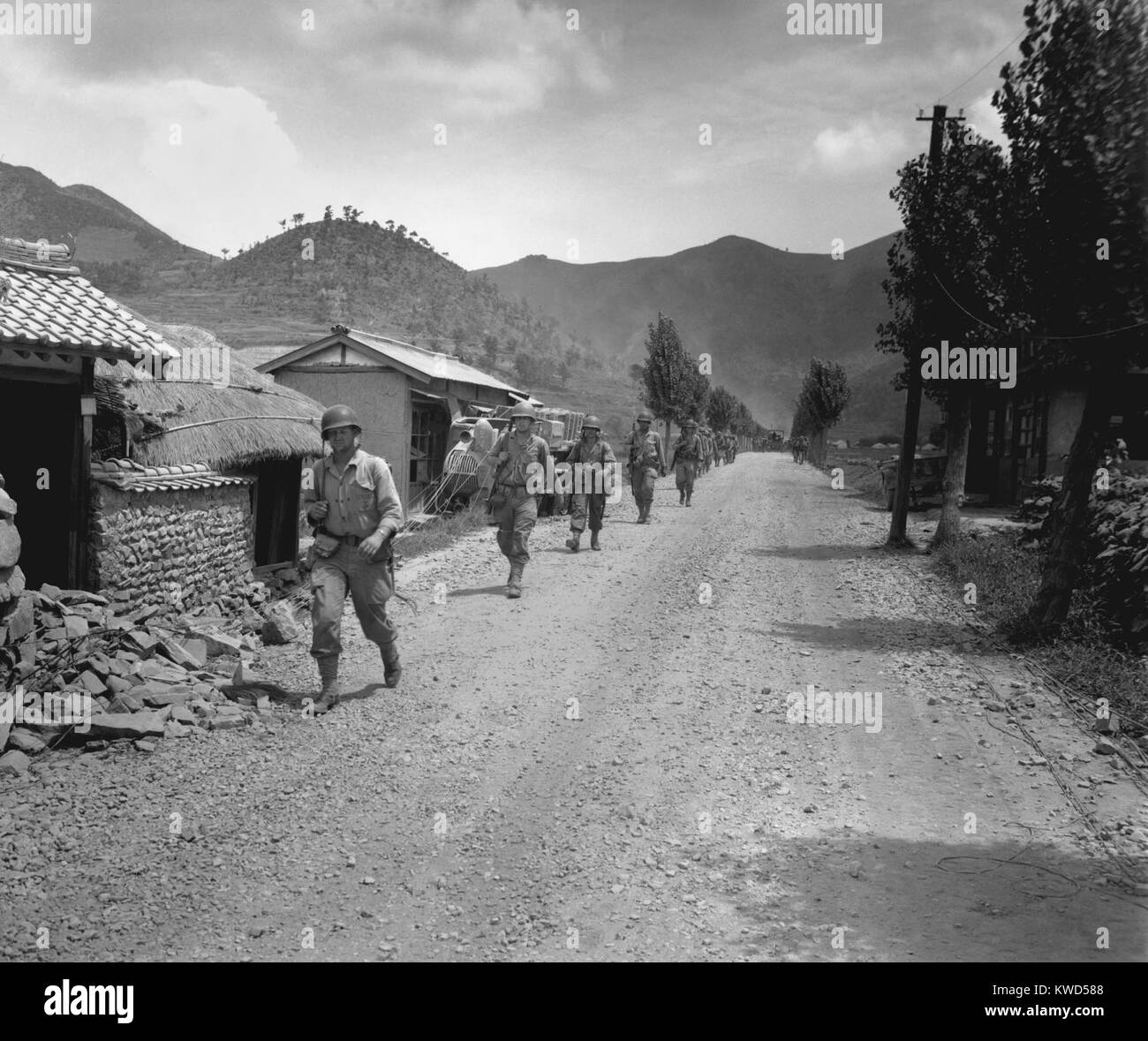 U.S. Marines pass through one of the many small, battered South Korean villages. They are moving up to meet the North Korean forces during the Battle of Pusan Perimeter. Korean War, 1950-53. (BSLOC 2014 11 24) Stock Photo