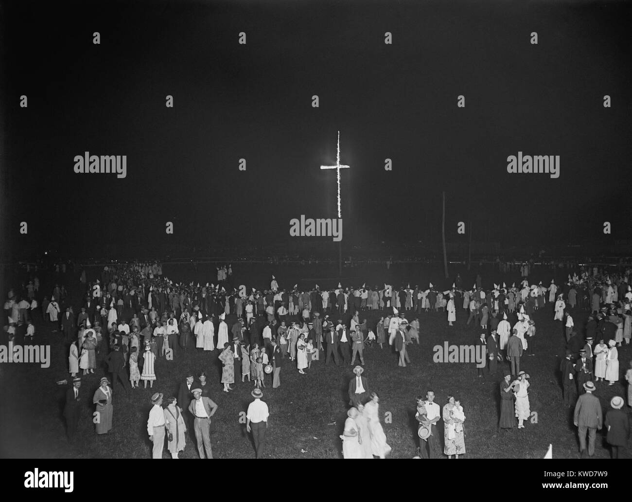 Burning of 80 ft. cross at a Ku Klux Klan rally in Arlington, Virginia, August 9, 1925. Men, women, and some families in street clothes gather in small groups as shrouded Klansmen make a circle around the burning cross. (BSLOC 2015 16 177) Stock Photo