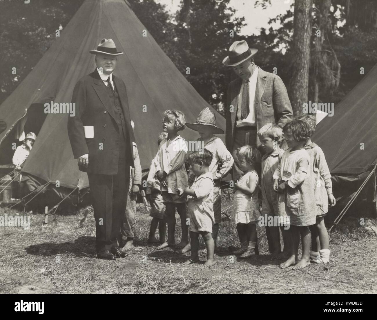 Herbert Hoover with girls and boys at a tent camp during the Great Mississippi River Flood in 1927. The worst effected states were Arkansas, Mississippi, and Louisiana. Hoover, then Sec. of Commerce, was named by President Coolidge to coordinate flood relief with the American Red Cross. (BSLOC 2015 16 67) Stock Photo