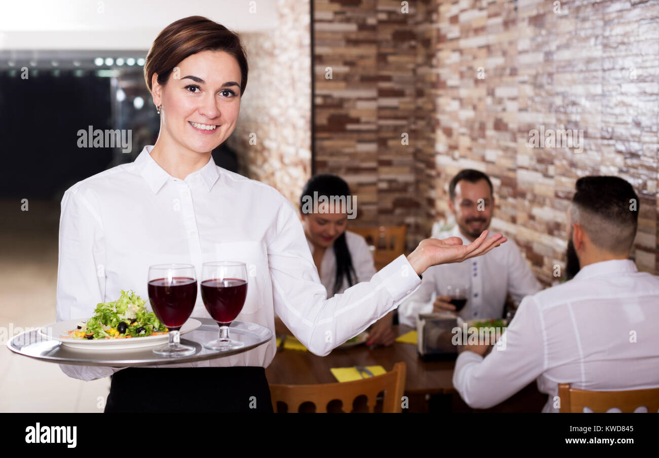 Smiling female waiter welcoming guests to country restaurant Stock Photo