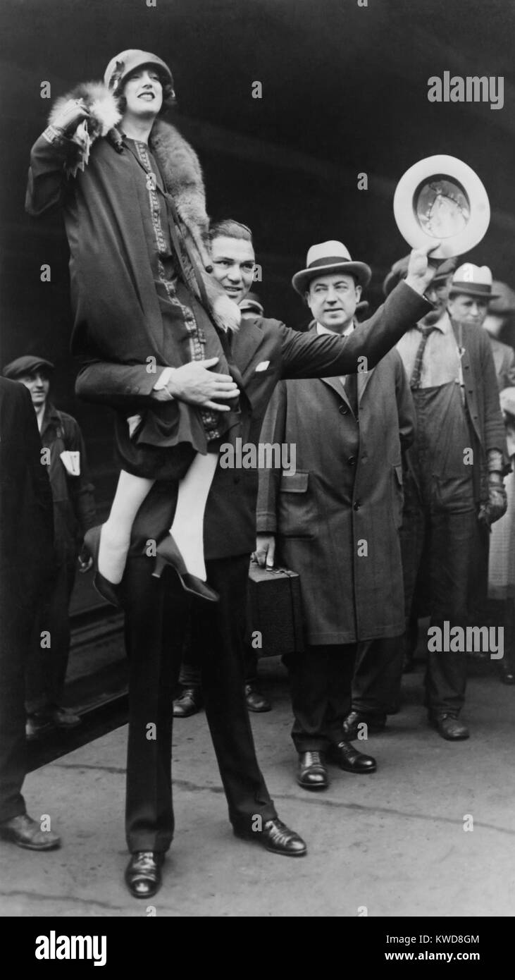 Boxer Jack Dempsey in Chicago, hoisting his bride, Estelle Taylor, on his right shoulder. April 22, 1925. The movie actress was his second wife. (BSLOC 2015 17 74) Stock Photo