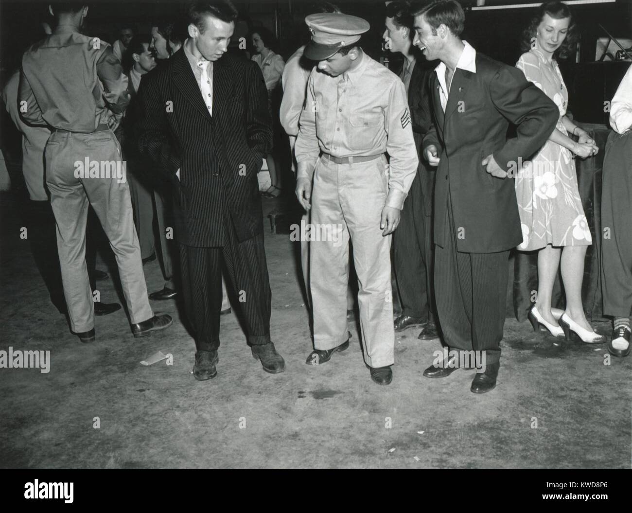 Soldier inspects Zoot Suiters at an intermission of Woody Herman's Orchestra engagement. At the Uline Arena, Washington, D.C., June 1942. Oversized Zoot Suits flaunted World War 2 fabric rationing, and later because as source of street fighting between Zo (BSLOC_2016_7_9) Stock Photo