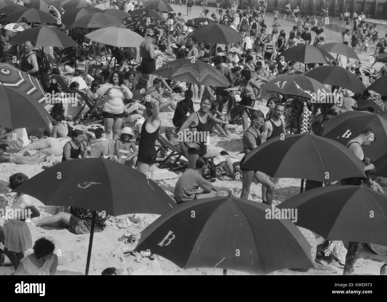 Long Beach in New York City, 1927. Packed with umbrellas and sun bathers on the south shore of western Long Island. Men still wore tank tops, but both sexes bathing suits were getting briefer as the 1920s progressed (BSLOC 2016 8 95) Stock Photo