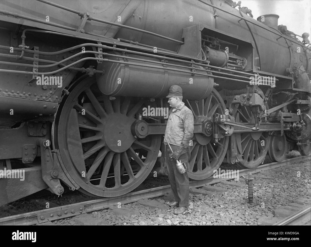 Mechanic servicing a railway steam engine in 1924. Massive locomotives has increased speed and power to move heavier loads (BSLOC 2016 10 178) Stock Photo