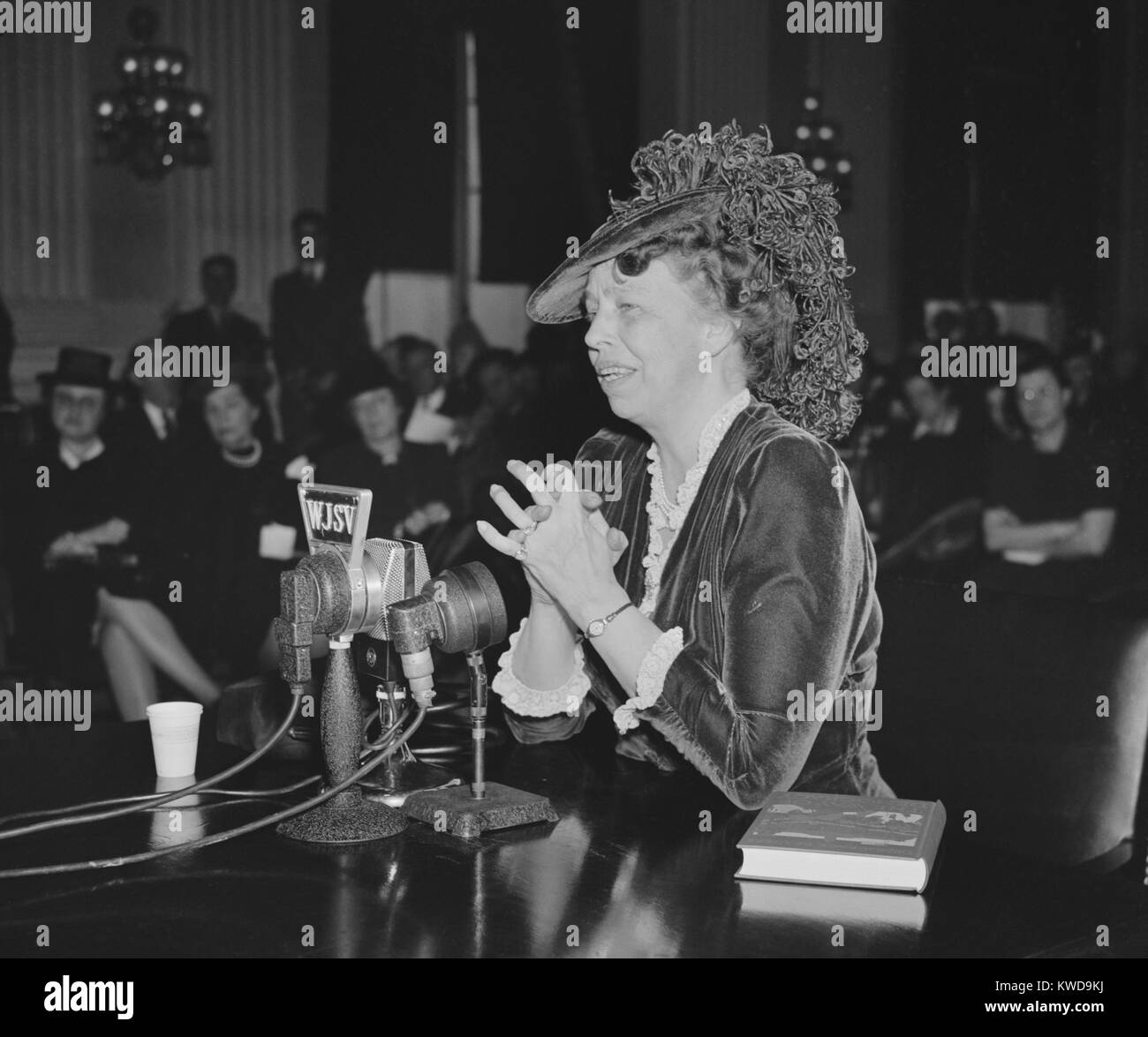 First Lady Eleanor Roosevelt speaking and wearing an adventurous ostrich feathered hat. 1930s. A book, 'The Way to Democracy', is beside her (BSLOC 2016 10 211) Stock Photo