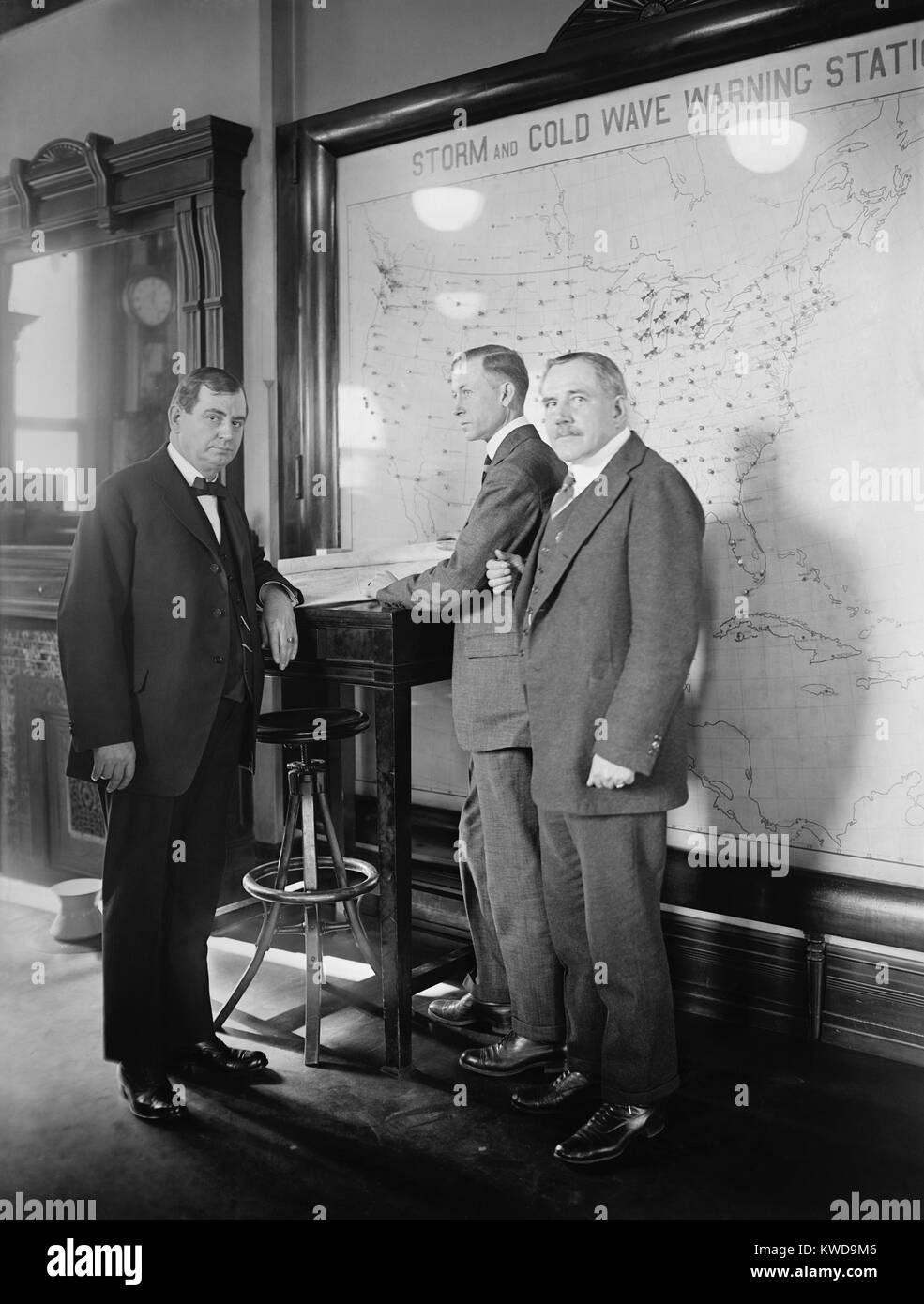 Meteorologists at the U.S. Weather Bureau stand in front of a map of the 48 states in 1924. Their map it titled, 'Warm and Cold Wave Warning Stations'. Wind speed and altitude data was collected by Weather Bureau reports from across the nation. L-R: Secretary Gore; R.H. Weightman; C.F. Marvin (BSLOC 2016 10 28) Stock Photo