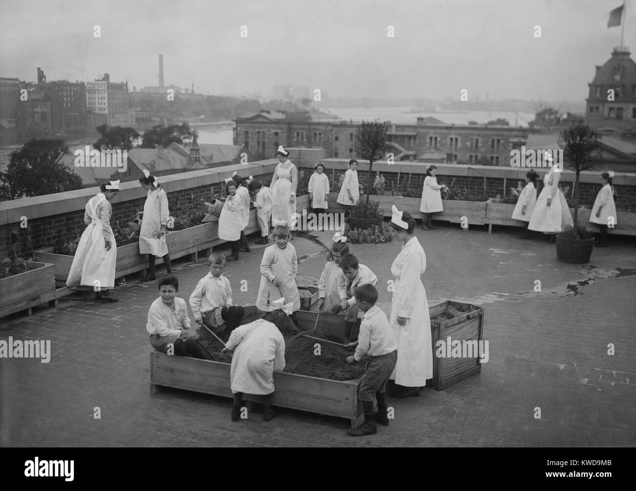 Children's roof garden at Ellis Island offered relief from boredom for young detainees, c.1910s. They were held back from U.S. entry because a parent was quarantined. Some of the girls wear long shirts with stenciled letters near their knee length hems (BSLOC 2016 10 30) Stock Photo