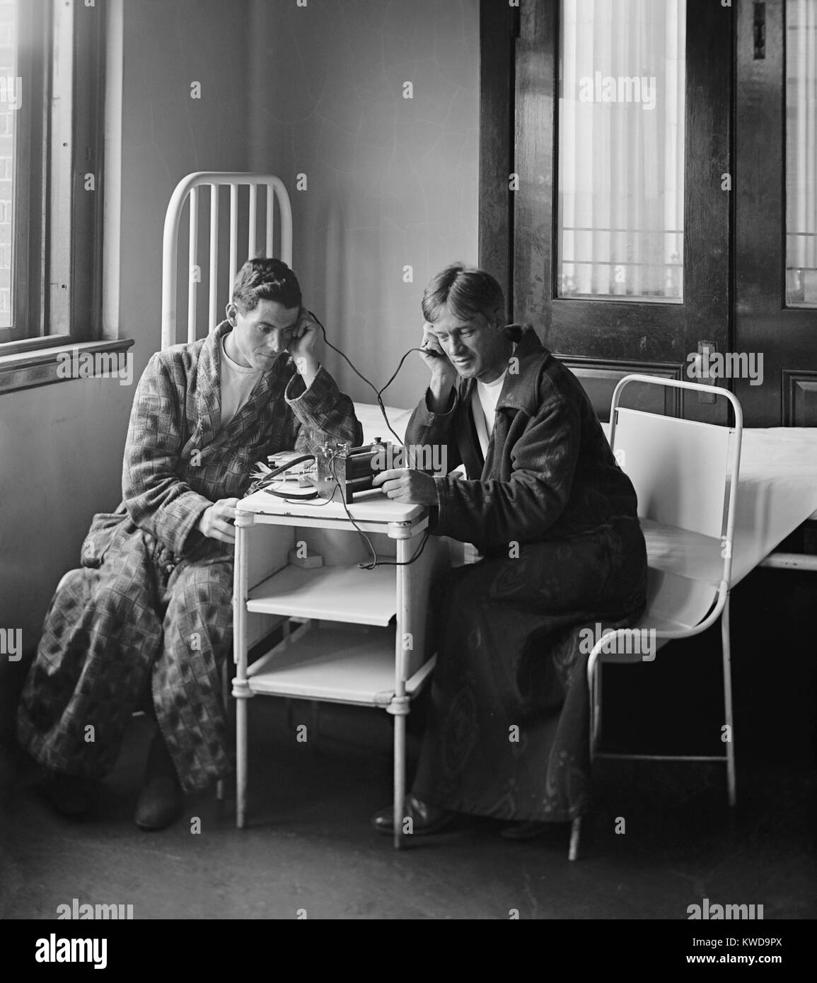 Patients in bathrobes listening to a radio at Garfield Hospital, in 1924. Radio entertained many and eased the isolation of those confined by illness. Garfield Hospital was located on Florida Avenue NW between 10th and 11th streets, Washington, D.C., from 1884-1958 (BSLOC 2016 10 54) Stock Photo