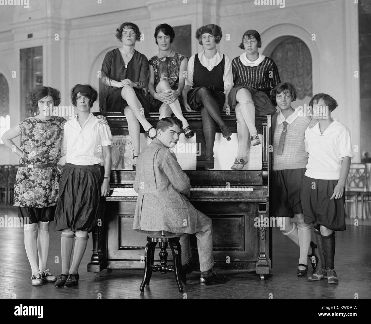 Group of young women described as 'Debutantes' wearing bloomers around a man at a piano. Oct 8, 1923. Washington, D.C. vicinity, (BSLOC_2015_17_209) Stock Photo