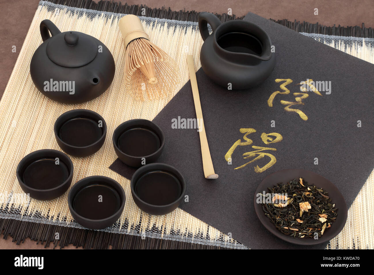 Green jasmine tea with yin and yang chinese calligraphy script, teapot, cups, scoop, whisk and