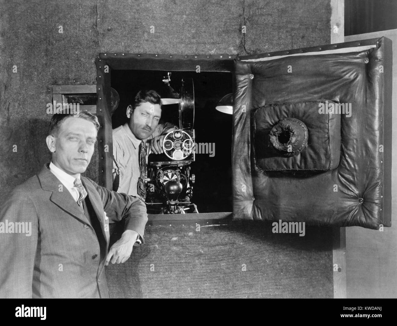 Soundproof camera booth designed to allowed actors voices to be recorded while filming, 1926. Designed by Western Electric Company, the 1926 booth was mounted on wheels to allow movement. It is inspected by H.C. Humphrey (left) of Bell Telephone Laboratories and Charles E. Davis (right), a Warner Brothers cameraman (BSLOC 2016 10 19) Stock Photo