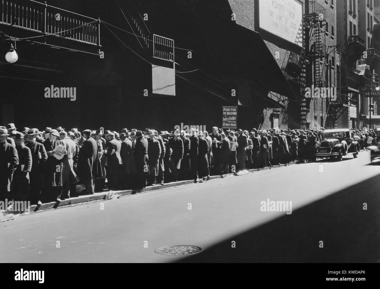 New York men in a bread line during the Great Depression, 1935-38. The sign read, 'Paid Up to this Point, Every Dollar pays for 20 More Meals. Men ahead of the sign are assured of a five-cent meal--the rest must wait for more contributions.' Many men went to soup kitchens so their families would have more to eat at home (BSLOC 2016 10 210) Stock Photo